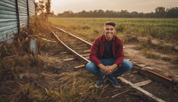 solo,looking at viewer,smile,short hair,shirt,black hair,1boy,holding,sitting,jacket,male focus,outdoors,open clothes,shoes,teeth,pants,black footwear,grin,open jacket,tree,black shirt,facial hair,grass,denim,sneakers,scenery,red jacket,jeans,blue pants,very short hair,undercut,fishing rod,fishing,brown hair,full body,boots,sky,day,squatting,own hands together,sunset,blue footwear,realistic,indian style,field,photo background,railroad tracks