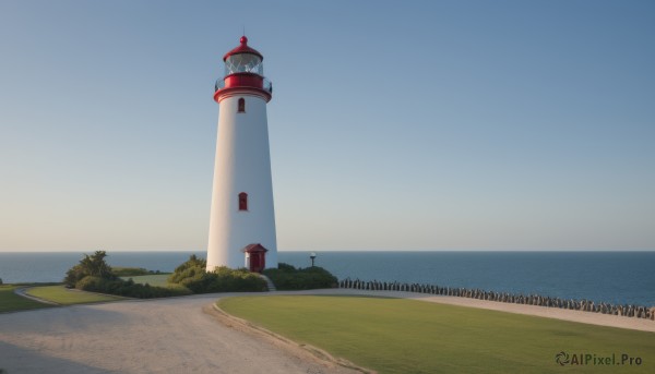 outdoors,sky,day,water,tree,blue sky,no humans,ocean,beach,grass,building,scenery,horizon,clock,road,bush,lamppost,tower,shore,path,lighthouse,sand