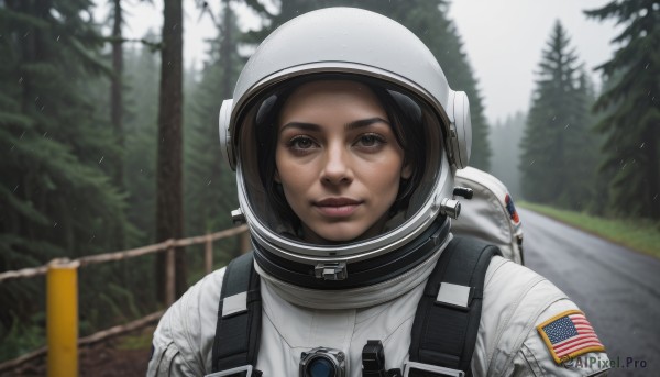 1girl,solo,looking at viewer,smile,brown hair,black hair,brown eyes,closed mouth,upper body,outdoors,blurry,tree,lips,depth of field,blurry background,helmet,nature,forest,realistic,american flag,spacesuit,japanese flag,space helmet,astronaut,short hair,parted lips,backpack,portrait,snow,pine tree