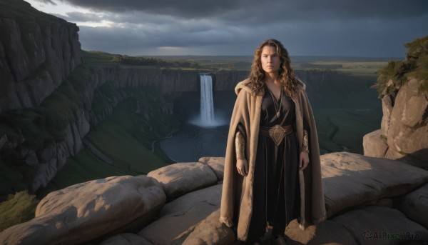 1girl,solo,long hair,breasts,looking at viewer,brown hair,long sleeves,dress,brown eyes,jewelry,closed mouth,standing,outdoors,sky,day,cloud,hood,water,cape,black dress,tree,lips,cloudy sky,scenery,cloak,robe,rock,mountain,fantasy,arms at sides,bracer,river,waterfall,cliff,necklace,ocean