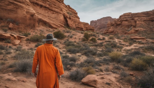 solo,gloves,long sleeves,1boy,hat,standing,male focus,outdoors,sky,day,cloud,from behind,coat,scenery,rock,facing away,black hair,weapon,sword,mountain,orange jacket,desert