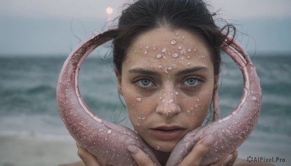 1girl,solo,looking at viewer,short hair,blue eyes,black hair,holding,closed mouth,outdoors,sky,day,water,blurry,lips,fingernails,grey eyes,hands up,depth of field,blurry background,ocean,beach,portrait,tentacles,realistic,sand,straight-on,octopus,brown hair,1boy,male focus,facial mark