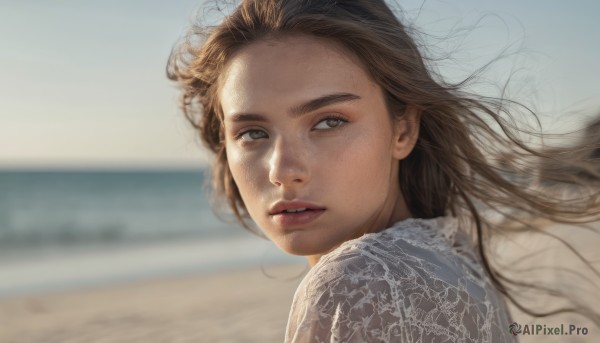 1girl, solo, long hair, looking at viewer, brown hair, shirt, brown eyes, white shirt, upper body, outdoors, parted lips, day, blurry, lips, looking to the side, floating hair, blurry background, beach, wind, freckles, realistic, nose