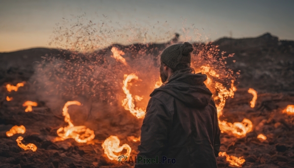 solo, 1boy, hat, upper body, male focus, outdoors, sky, hood, from behind, blurry, coat, hood down, fire, scenery, mountain, beanie, facing away, burning