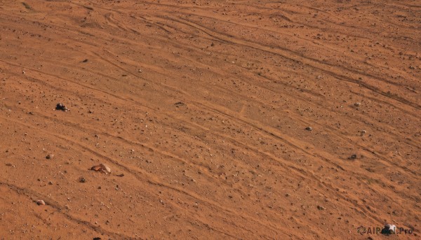 1girl,solo,outdoors,shadow,from above,scenery,rock,sand,wide shot,desert,footprints,very wide shot,monochrome,no humans,orange theme,dust