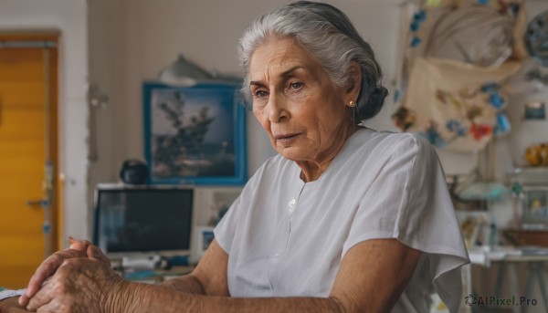 1girl,solo,looking at viewer,smile,shirt,1boy,jewelry,sitting,closed mouth,white shirt,upper body,white hair,short sleeves,grey hair,earrings,indoors,hair bun,blurry,grey eyes,blurry background,chair,single hair bun,own hands together,realistic,old,old man,photo background,arm hair,old woman,wrinkled skin,short hair,depth of field