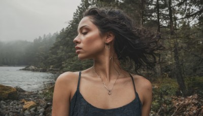 1girl,solo,long hair,blue eyes,brown hair,black hair,bare shoulders,jewelry,collarbone,upper body,earrings,outdoors,day,water,necklace,tree,lips,looking to the side,profile,floating hair,looking away,wind,nature,scenery,forest,rock,realistic,nose,river,breasts,dress,sleeveless,mole,black dress,hoop earrings,spaghetti strap