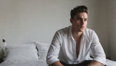 solo,looking at viewer,blue eyes,brown hair,shirt,black hair,1boy,sitting,white shirt,upper body,male focus,parted lips,open clothes,collared shirt,indoors,lips,looking to the side,pillow,open shirt,dress shirt,bed,facial hair,on bed,realistic,stubble,lamp,real life insert,short hair,closed mouth,undercut,partially unbuttoned,chest hair