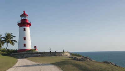 outdoors,sky,day,water,tree,blue sky,no humans,ocean,beach,grass,building,scenery,sand,palm tree,horizon,road,castle,tower,shore,rock,bush,lighthouse