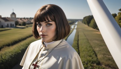 1girl,solo,looking at viewer,smile,short hair,bangs,brown hair,brown eyes,jewelry,closed mouth,upper body,outdoors,sky,day,blunt bangs,necklace,blurry,tree,lips,grey eyes,capelet,depth of field,blurry background,bob cut,grass,cross,building,realistic,nose,cross necklace,white capelet,latin cross,blue eyes,dress,blue sky,portrait,scenery