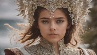 1girl,solo,long hair,looking at viewer,brown hair,hair ornament,brown eyes,closed mouth,outdoors,artist name,blurry,lips,eyelashes,floating hair,depth of field,blurry background,feathers,wind,portrait,freckles,realistic,jewelry,day,armor,gem,headdress