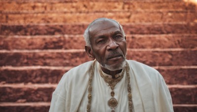 solo,looking at viewer,short hair,1boy,jewelry,closed mouth,upper body,white hair,grey hair,male focus,necklace,blurry,black eyes,facial hair,beard,robe,stairs,realistic,mustache,bald,old,old man,photo background,white robe,wrinkled skin,smile,dark skin,grey eyes,chain,scar,dark-skinned male,scar on face,brick wall,gold chain