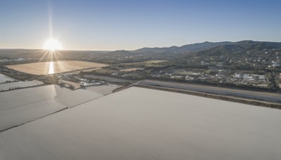 outdoors,sky,day,cloud,water,blue sky,no humans,sunlight,building,scenery,lens flare,sunset,mountain,city,sun,horizon,road,cityscape,river,landscape,mountainous horizon,sunrise,hill,desert