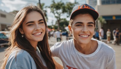 1girl,long hair,looking at viewer,smile,open mouth,brown hair,shirt,1boy,hat,brown eyes,jewelry,white shirt,upper body,earrings,outdoors,teeth,day,necklace,grin,blurry,black eyes,tree,lips,depth of field,blurry background,t-shirt,building,baseball cap,realistic,selfie,sunlight,thick eyebrows,blue shirt,ground vehicle,motor vehicle,car,crowd,photo background,real life insert