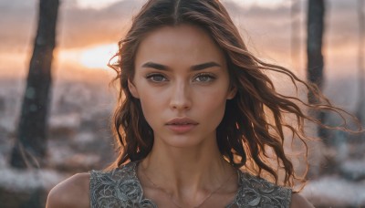 1girl,solo,long hair,looking at viewer,brown hair,brown eyes,jewelry,closed mouth,collarbone,upper body,outdoors,necklace,blurry,lips,depth of field,blurry background,wavy hair,portrait,forehead,realistic,nose,parted lips,tree,floating hair,sunlight,thick eyebrows,wind,close-up,backlighting,sunset