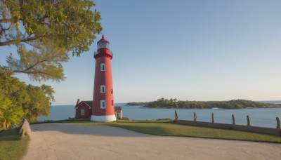 outdoors,sky,day,water,tree,blue sky,no humans,ocean,beach,grass,building,nature,scenery,fence,horizon,clock,road,bush,house,tower,shore,path,sunset,lighthouse