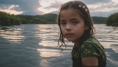 1girl,solo,long hair,looking at viewer,brown hair,shirt,black hair,hair ornament,brown eyes,closed mouth,upper body,flower,short sleeves,outdoors,parted lips,sky,day,cloud,hair flower,water,blurry,from side,tree,lips,looking to the side,depth of field,blurry background,sunlight,cloudy sky,child,nature,forehead,reflection,mountain,realistic,nose,green shirt,female child,river,lake,scenery