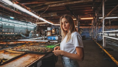 1girl,solo,long hair,looking at viewer,blonde hair,brown hair,shirt,holding,brown eyes,white shirt,short sleeves,solo focus,pants,dark skin,bag,dark-skinned female,lips,denim,t-shirt,jeans,realistic,photo background,train station,railroad tracks,real world location,indoors,scenery