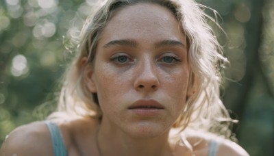 1girl,solo,long hair,looking at viewer,blonde hair,bare shoulders,jewelry,green eyes,earrings,parted lips,teeth,blurry,lips,grey eyes,depth of field,blurry background,sunlight,portrait,freckles,realistic,bokeh,outdoors,day,thick eyebrows,close-up,nose,dappled sunlight,mole on cheek