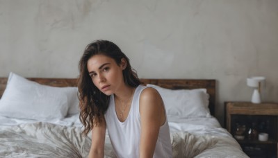 1girl,solo,long hair,looking at viewer,brown hair,shirt,black hair,brown eyes,jewelry,sitting,white shirt,upper body,sleeveless,indoors,dark skin,necklace,dark-skinned female,lips,pillow,bed,on bed,tank top,messy hair,freckles,realistic,lamp,bedroom,white tank top,photo inset,dress,white dress,mole,flat chest