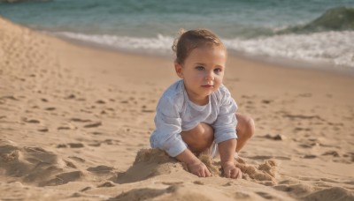 1girl,solo,looking at viewer,short hair,blue eyes,brown hair,shirt,long sleeves,closed mouth,white shirt,outdoors,shorts,day,water,hair bun,blurry,lips,blurry background,ocean,beach,squatting,single hair bun,child,realistic,sand,female child,sand sculpture,barefoot,dark skin,dark-skinned female,rock,shore