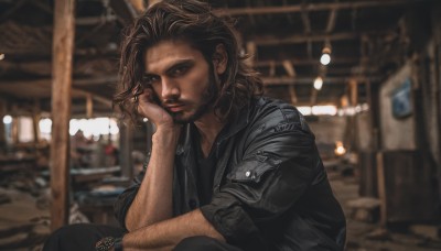 solo,looking at viewer,brown hair,shirt,1boy,brown eyes,sitting,closed mouth,jacket,short sleeves,male focus,pants,indoors,dark skin,medium hair,blurry,black jacket,black shirt,depth of field,blurry background,facial hair,black pants,dark-skinned male,beard,hand on own face,sleeves rolled up,watch,head rest,realistic,wristwatch,leather,leather jacket,photo background,arm hair,lips,stubble