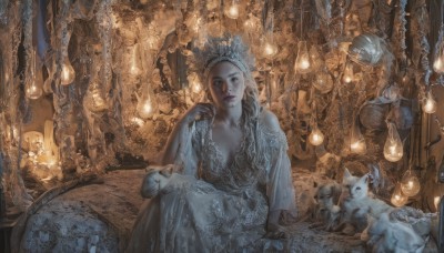 1girl,solo,long hair,breasts,looking at viewer,blue eyes,blonde hair,dress,cleavage,jewelry,medium breasts,sitting,braid,earrings,indoors,white dress,lips,arm support,animal,cat,tiara,crown,realistic,fantasy,candle,statue,chandelier,chair,head rest,throne,elbow rest