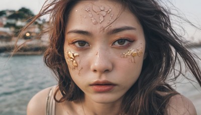 1girl,solo,long hair,looking at viewer,brown hair,black hair,brown eyes,closed mouth,outdoors,parted lips,day,water,blurry,lips,depth of field,blurry background,portrait,freckles,realistic,red lips,floating hair,ocean,wind,close-up,forehead,nose