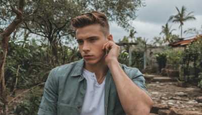 solo,looking at viewer,short hair,brown hair,shirt,1boy,brown eyes,closed mouth,jacket,white shirt,upper body,male focus,outdoors,open clothes,sky,day,cloud,blurry,open jacket,tree,blurry background,facial hair,denim,realistic,photo background,arm hair,denim jacket,blue eyes,collared shirt,hand up,signature,phone,plant,blue jacket,hand on own face,undercut,talking on phone