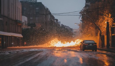 outdoors,sky,day,cloud,tree,no humans,fire,ground vehicle,building,scenery,motor vehicle,reflection,sunset,city,car,road,explosion,power lines,lamppost,street,utility pole,truck,real world location,solo,window,snow