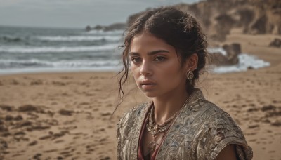 1girl,solo,looking at viewer,short hair,blue eyes,brown hair,black hair,hair ornament,brown eyes,jewelry,upper body,earrings,outdoors,parted lips,day,dark skin,water,necklace,blurry,dark-skinned female,lips,depth of field,blurry background,ocean,beach,realistic,nose,sand,desert,breasts,dress,wind,portrait,freckles,waves,shore