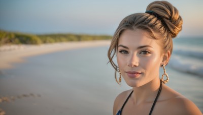 1girl,solo,looking at viewer,smile,short hair,brown hair,bare shoulders,brown eyes,jewelry,closed mouth,collarbone,swimsuit,bikini,earrings,outdoors,day,water,hair bun,blurry,lips,depth of field,blurry background,ocean,beach,single hair bun,portrait,blue bikini,hoop earrings,realistic,sand,upper body,sky,necklace,blue sky,freckles,nose