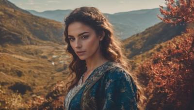 1girl,solo,long hair,looking at viewer,blue eyes,brown hair,dress,jewelry,closed mouth,upper body,earrings,outdoors,sky,day,blurry,from side,tree,lips,eyelashes,blurry background,blue dress,wavy hair,nature,curly hair,mountain,realistic,nose,field,breasts,necklace,depth of field,sunlight,scenery,freckles,autumn leaves,autumn