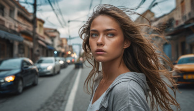 1girl, solo, long hair, blue eyes, brown hair, upper body, outdoors, parted lips, sky, hood, blurry, lips, depth of field, blurry background, ground vehicle, building, motor vehicle, freckles, city, realistic, car, road, street