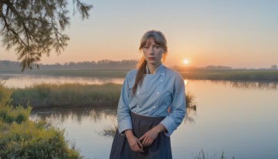 1girl,solo,long hair,looking at viewer,bangs,blue eyes,skirt,brown hair,shirt,long sleeves,holding,standing,white shirt,ponytail,cowboy shot,outdoors,parted lips,sky,black skirt,water,tree,lips,blue skirt,buttons,sunlight,own hands together,grass,blue shirt,plant,scenery,backlighting,reflection,sunset,long skirt,realistic,sun,river,lake,brown eyes,jewelry,landscape