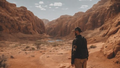 solo,short hair,brown hair,long sleeves,1boy,hat,holding,standing,jacket,weapon,male focus,outdoors,sky,day,pants,cloud,bag,from behind,blue sky,black jacket,gun,black headwear,backpack,cloudy sky,holding gun,scenery,baseball cap,rock,mountain,sand,brown pants,desert,black hair,brown theme