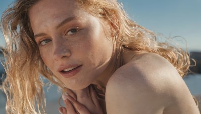 1girl,solo,long hair,looking at viewer,smile,blue eyes,blonde hair,bare shoulders,jewelry,nude,outdoors,parted lips,sky,teeth,day,water,blurry,lips,looking to the side,depth of field,blurry background,wavy hair,own hands together,portrait,freckles,realistic,nose,open mouth,brown hair,earrings,blue sky,fingernails,eyelashes,thick eyebrows,close-up