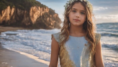 1girl,solo,long hair,looking at viewer,blue eyes,blonde hair,brown hair,hair ornament,dress,closed mouth,upper body,flower,outdoors,sky,sleeveless,day,hair flower,water,blurry,lips,depth of field,blurry background,blue dress,ocean,wavy hair,beach,freckles,realistic,nose,head wreath,cloud,blue sky,sunlight,rock,sand,waves,shore,cliff