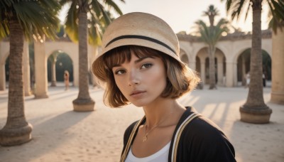 1girl,solo,looking at viewer,short hair,bangs,multiple girls,brown hair,shirt,hat,brown eyes,jewelry,collarbone,jacket,white shirt,upper body,outdoors,parted lips,solo focus,day,necklace,blurry,tree,lips,black jacket,depth of field,blurry background,sunlight,portrait,sun hat,realistic,nose,palm tree,straw hat,bag,backpack,pendant