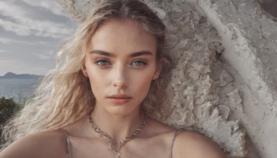 1girl,solo,long hair,looking at viewer,blue eyes,blonde hair,bare shoulders,jewelry,closed mouth,collarbone,upper body,earrings,outdoors,sky,day,cloud,necklace,tree,lips,grey eyes,cloudy sky,portrait,mountain,realistic,nose,wavy hair,expressionless