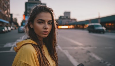 1girl,solo,long hair,looking at viewer,brown hair,black hair,brown eyes,upper body,outdoors,parted lips,teeth,dark skin,hood,blurry,dark-skinned female,lips,looking to the side,hoodie,depth of field,blurry background,hood down,ground vehicle,building,motor vehicle,freckles,city,realistic,nose,car,road,street,photo background,yellow hoodie,shirt,jewelry,earrings,day,thick eyebrows,messy hair,forehead,stud earrings