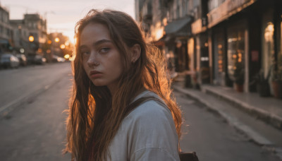 1girl, solo, long hair, looking at viewer, brown hair, shirt, jewelry, closed mouth, white shirt, upper body, earrings, outdoors, bag, blurry, lips, depth of field, blurry background, backpack, freckles, city, realistic, nose, road, street