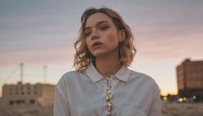 1girl,solo,looking at viewer,brown hair,shirt,brown eyes,jewelry,white shirt,upper body,earrings,outdoors,parted lips,sky,collared shirt,medium hair,blurry,black eyes,lips,dutch angle,buttons,depth of field,blurry background,building,freckles,pocket,sunset,city,realistic,breast pocket,short hair