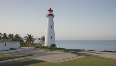 outdoors,sky,day,water,tree,blue sky,no humans,ocean,beach,grass,building,scenery,sand,palm tree,horizon,road,bush,tower,shore,lighthouse