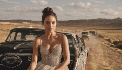 1girl,solo,breasts,looking at viewer,brown hair,black hair,dress,cleavage,bare shoulders,brown eyes,medium breasts,collarbone,outdoors,sky,day,cloud,hair bun,white dress,lips,single hair bun,ground vehicle,motor vehicle,mountain,realistic,car,vehicle focus,real life insert,desert,mole