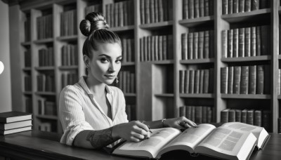 1girl,solo,looking at viewer,shirt,jewelry,sitting,closed mouth,monochrome,upper body,greyscale,earrings,striped,indoors,dark skin,hair bun,blurry,bracelet,dark-skinned female,lips,book,tattoo,table,single hair bun,ring,sleeves rolled up,open book,realistic,nose,bookshelf,pen,pencil,topknot,book stack,library,smile,reading,sleeves pushed up