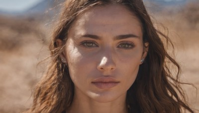 1girl,solo,long hair,looking at viewer,brown hair,brown eyes,jewelry,closed mouth,green eyes,earrings,outdoors,day,mole,blurry,lips,eyelashes,blurry background,piercing,sunlight,portrait,freckles,realistic,nose,mole on cheek,sky,wavy hair,wind,messy hair,close-up,dirty,desert