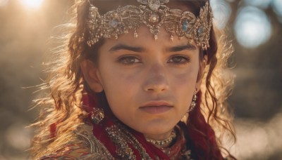 1girl,solo,long hair,looking at viewer,blonde hair,brown hair,hair ornament,brown eyes,jewelry,closed mouth,earrings,dark skin,necklace,blurry,lips,depth of field,blurry background,gem,portrait,freckles,curly hair,circlet,realistic,nose,tiara,close-up