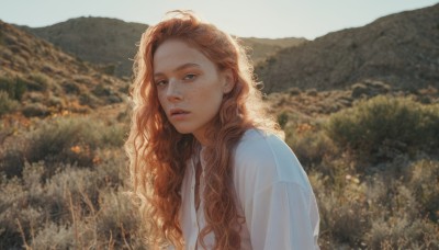 1girl,solo,long hair,looking at viewer,blue eyes,brown hair,shirt,white shirt,upper body,outdoors,parted lips,day,blurry,from side,lips,blurry background,wavy hair,nature,freckles,curly hair,mountain,realistic,nose,field,dress,sky,orange hair,tree,depth of field,sunlight