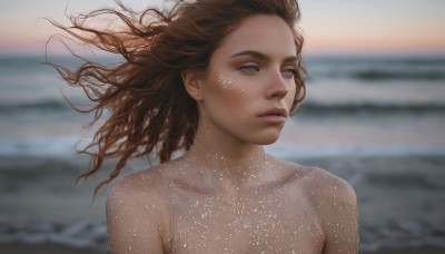 1girl,solo,long hair,blue eyes,brown hair,collarbone,upper body,nude,outdoors,parted lips,dark skin,water,blurry,lips,floating hair,blurry background,ocean,looking away,beach,wind,portrait,freckles,realistic,nose,sand,bare shoulders,closed mouth,mole,eyelashes,depth of field,facial mark,expressionless,messy hair,looking afar,waves